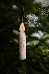 Decorative ornament with 'hope' text hanging on a Christmas tree.