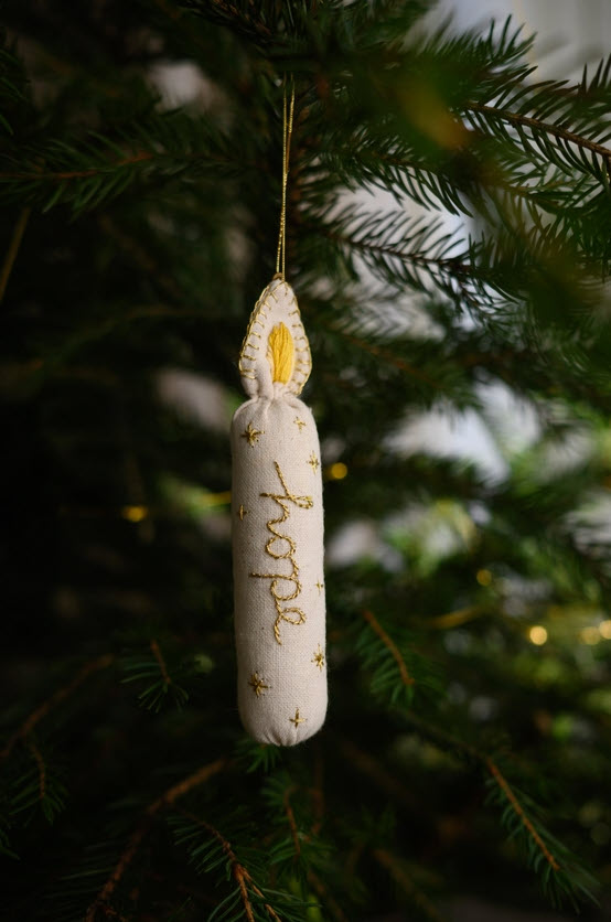 Decorative ornament with 'hope' text hanging on a Christmas tree.