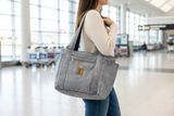 Woman carrying a gray tote bag in an airport setting