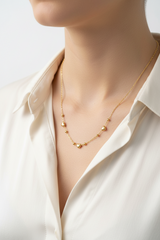 Gold heart chain necklace on a women with a white shirt