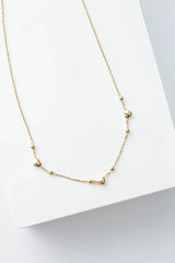 Gold heart chain necklace on a light gray background