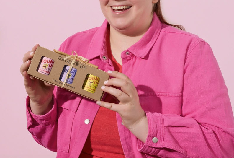 Person holding a box of 'Glow Up' products against a pink background