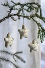 Star-shaped Christmas ornaments hanging from a tree branch with a blurred background