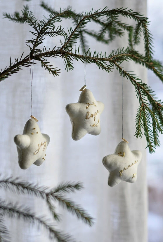 Star-shaped Christmas ornaments hanging from a tree branch with a blurred background